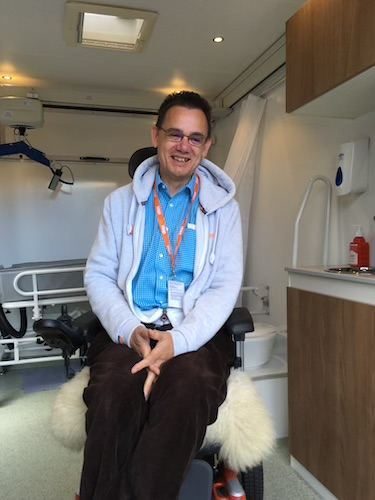 Paul smiling outdoors beside water and hills